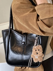 Minimalist black leather underarm tote bag with plush puppy pendant and double straps