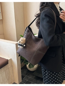Dettaglio della borsa tote marrone scuro con lettere in rilievo e cuciture a contrasto