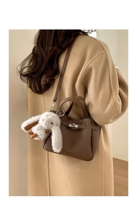 Détail du sac seau en cuir marron foncé avec charm lapin en peluche et boucle en métal