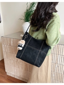 Dettaglio della borsa tote vintage nera con cuciture bianche e ciondolo orsetto di peluche