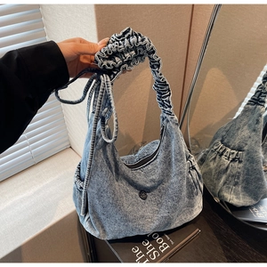 Detail of light blue denim bag featuring ruffled straps and ruched crescent design