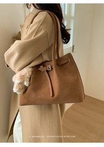 Brown suede tote bag detail featuring a fluffy paw charm and slender shoulder straps