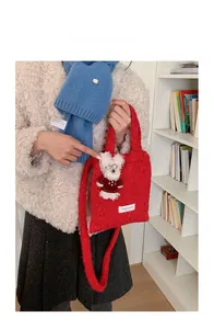 Close-up of a plush red tote bag featuring a cute white bear pendant on a shoulder strap