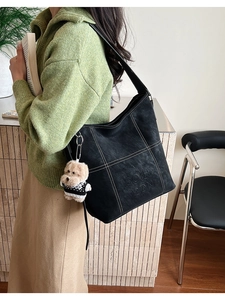 Dettaglio della borsa tote nera con cuciture bianche a contrasto e ciondolo a forma di cucciolo
