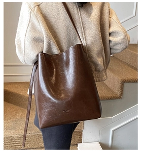 Detail of vintage oil wax leather tote bag with embossed logo and smooth glossy texture