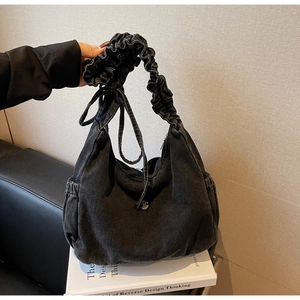 Detail of black washed denim hobo bag with M-logo buckle and pleated shoulder strap