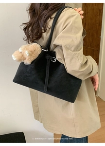 Detail of black vintage tote bag with adjustable silver buckle and plush animal paw charm