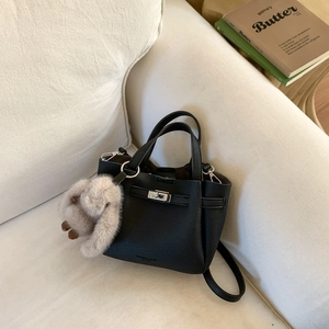 Détail du sac cabas en cuir noir avec fermoir rotatif argenté et breloque lapin
