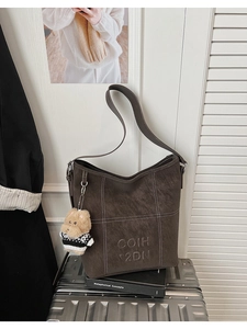 Dettaglio borsa tote vintage marrone con cuciture bianche e ciondolo a forma di orso