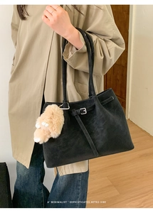 Retro black matte tote bag detail with minimalist strap and plush animal charm on model