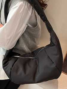 Large black padded nylon crossbody bag worn by model with wide strap and zipper