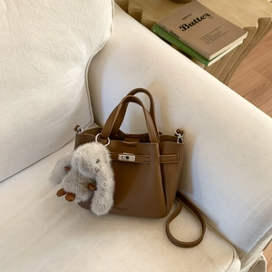 Détail du sac seau en cuir marron grainé avec fermoir argenté et breloque lapin en peluche