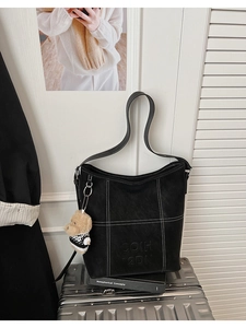 Dettaglio borsa tote in pelle nera opaca con cuciture a contrasto e ciondolo a forma di orso