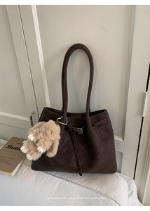 Detail of retro dark brown tote bag with suede texture and plush rabbit pendant