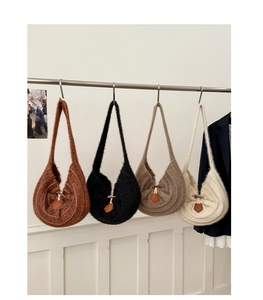 Detail of four knit shoulder bags in tan, black, grey, and cream with toggle closures