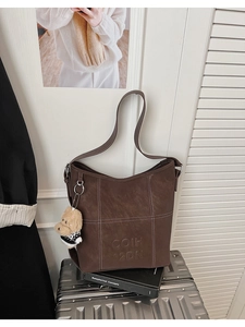 Dettaglio della borsa tote vintage marrone con cuciture a contrasto e ciondolo a cucciolo