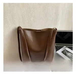 Brown vintage oil wax leather tote bag shown on desk with lifestyle accessories