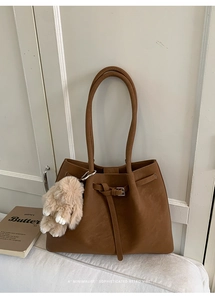 Close-up of vintage brown tote bag with metal buckle and soft plush rabbit charm