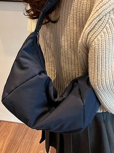 Navy blue large capacity crescent crossbody bag for winter shown on model from side back view