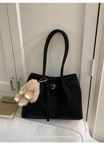 Detail of a vintage black faux suede tote bag with metal buckles and a cute rabbit charm