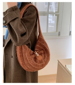 Detail of soft brown knit half-moon shoulder bag featuring a vintage horn buckle closure