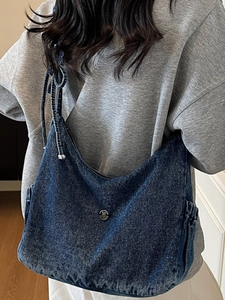 Retro denim shoulder bag in dark blue wash featuring a metal M buckle and bow details