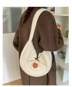 Detail of cream knit shoulder bag featuring horn button closure and brown leather trim
