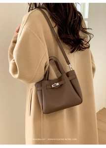 Détail du sac seau en cuir grainé marron foncé avec fermoir rotatif argenté et lanière