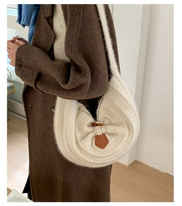 Detailed view of white knitted hobo bag with horn button and brown leather accent