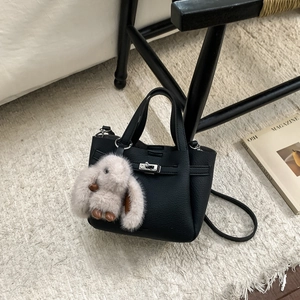 Détail du sac seau en cuir noir avec fermoir métallique et breloque lapin en peluche