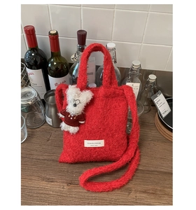 Detail of red plush knit shoulder bag with soft texture and white bear charm decoration