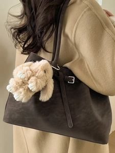 Brown suede tote bag with belt detail and plush rabbit pendant on shoulder