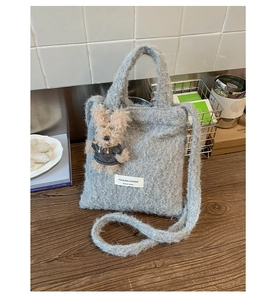 Macro detail of plush grey fuzzy tote bag featuring a cute puppy charm and brand label