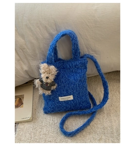 Detail of blue plush tote bag with lamb wool texture and cute teddy bear charm