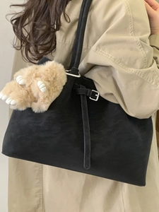 Vintage black suede tote bag with plush charm accessory worn with a beige trench coat