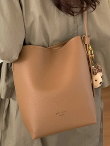 Brown faux leather bucket bag with bear charm and adjustable shoulder strap for women