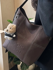 Borsa tote vintage marrone con cuciture a contrasto e ciondolo orsetto su modella donna