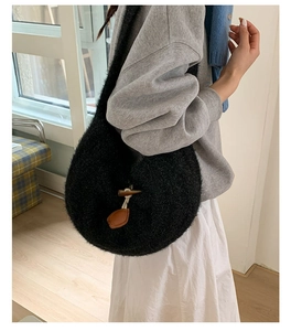 Detailed view of black fuzzy knit tote bag with brown horn buckle and soft plush texture