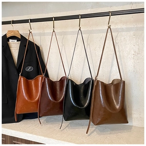 Detailed macro view of four vintage oil wax leather tote bags hanging in a row