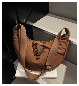 Close-up of caramel brown nylon dumpling bag featuring adjustable strap and zipper detail