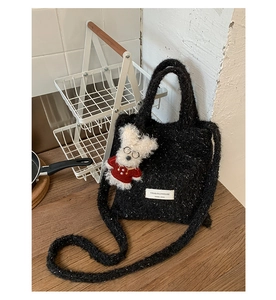 Close-up of fluffy black and white textured plush tote bag with a cute puppy doll charm