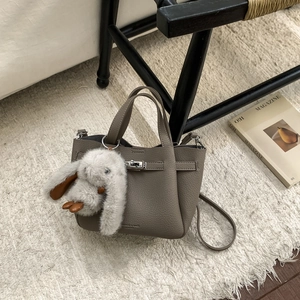 Sac seau en cuir gris avec fermoir rotatif argenté et charmant pendentif lapin en peluche