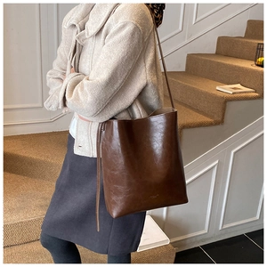 Detail of minimalist dark brown large bucket bag in glossy synthetic leather for daily use