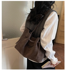 Close-up of a large dark brown suede tote bag with drawstring details and slim shoulder strap