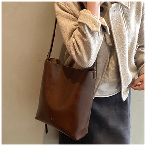 Detail of vintage brown leather bucket bag with adjustable strap and textured finish