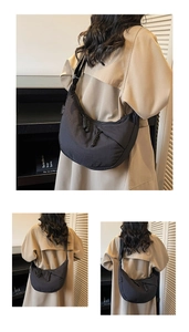 Detail of minimalist black nylon crescent bag with knot drawstring and woven label decoration
