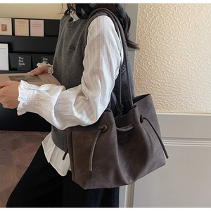 Detail of dark brown matte tote bag with side drawstring and long dual shoulder straps