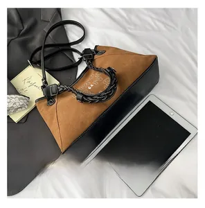 Detail of a brown suede and black leather patchwork tote bag with a chain strap