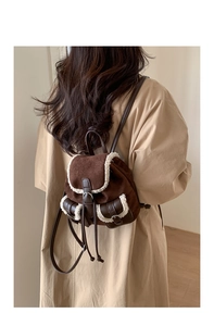 Detail of dark brown suede backpack with white faux fur trim and adjustable leather straps