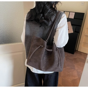 Detail of dark brown tote bag with drawstring shoulder straps and soft pleat design